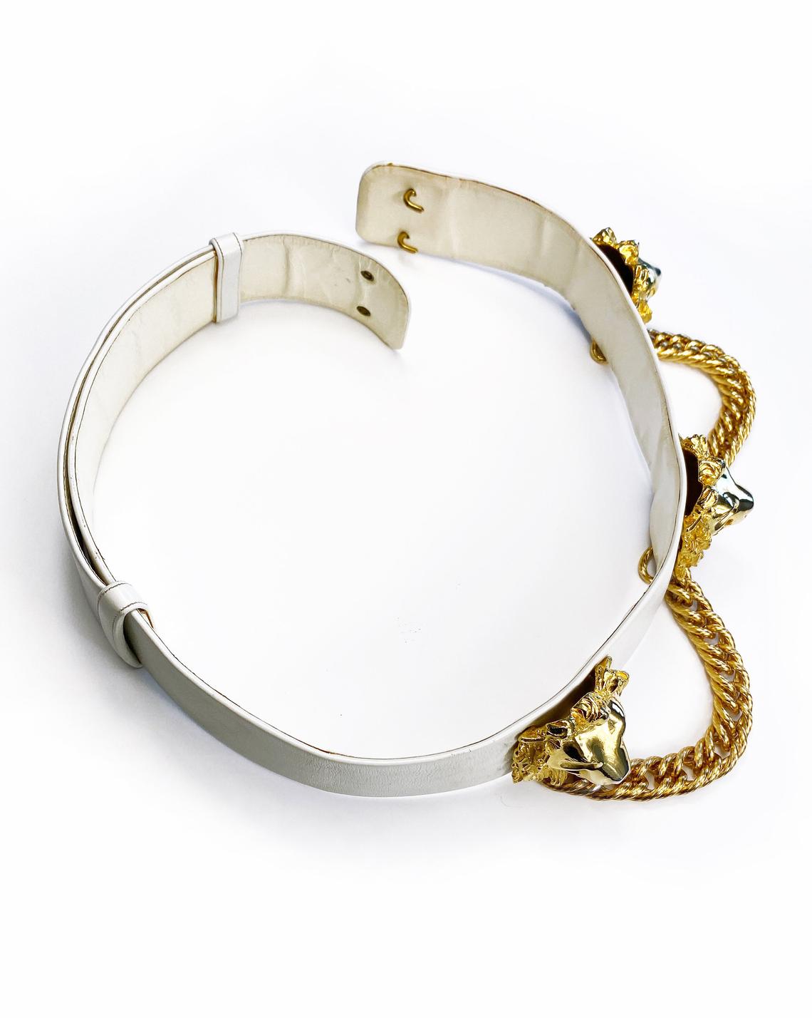 Fruit Vintage iconic Judith Leiber lion head belt with drop chains. This piece is amazing! It features 3 very large gold tone metal lions heads with drop chains on a white leather belt.