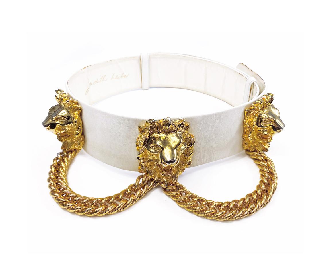Fruit Vintage iconic Judith Leiber lion head belt with drop chains. This piece is amazing! It features 3 very large gold tone metal lions heads with drop chains on a white leather belt.