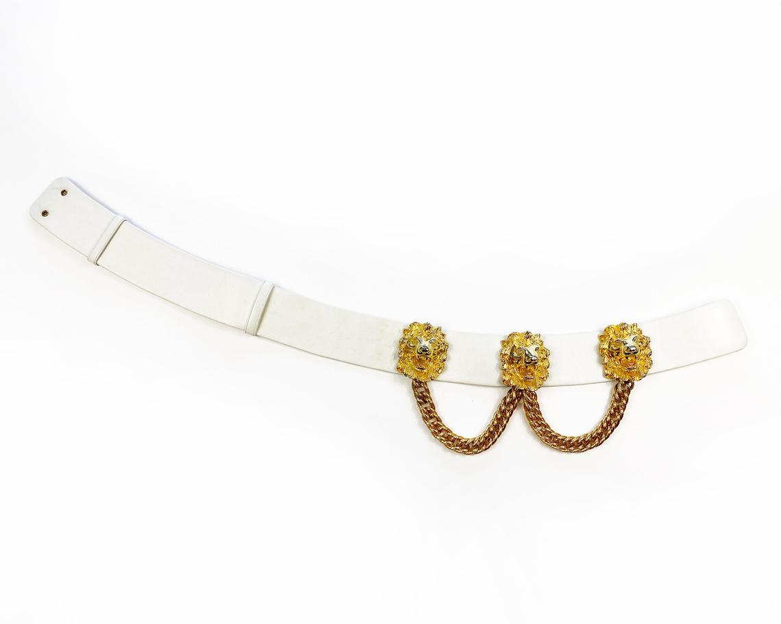 Fruit Vintage iconic Judith Leiber lion head belt with drop chains. This piece is amazing! It features 3 very large gold tone metal lions heads with drop chains on a white leather belt.
