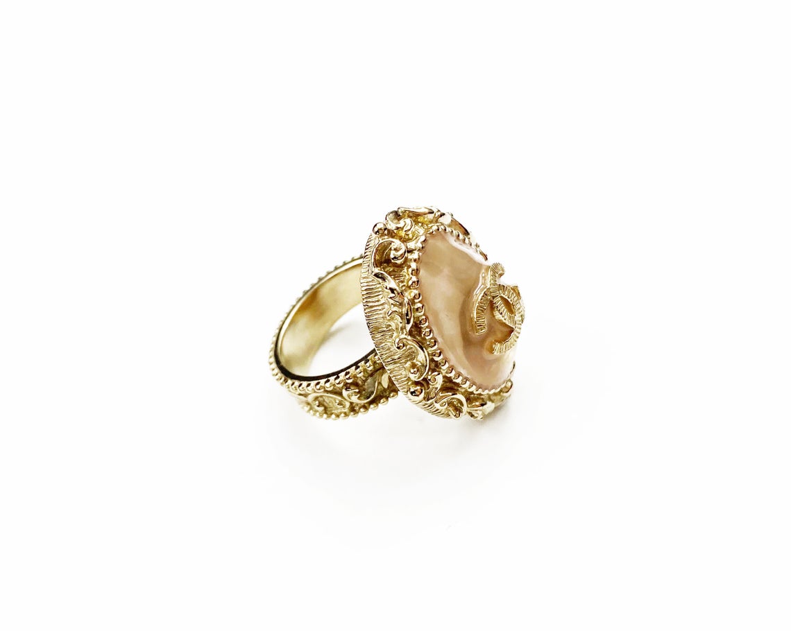 Fruit Vintage Chanel glass set logo ring. Features an ornate filigree style setting with pale pink glass stone with large CC logo inset.