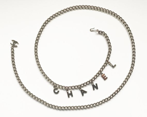 Fruit Vintage Chanel logo monogram letter chain belt in classic silver. Features a hook closure and logo drop Chanel CC charm.