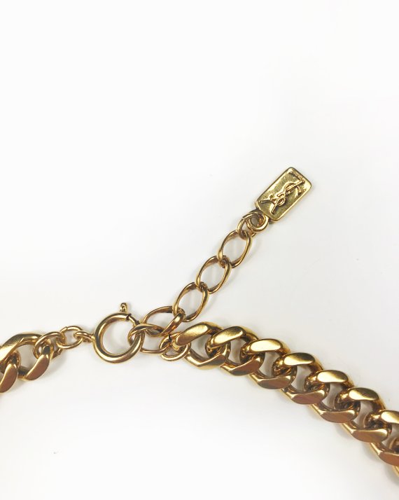Fruit Vintage rare 1980s Yves Saint Laurent 'lucky charm' medallion necklace with textured logo. It features heavy gold plating in a deep yellow tone and various iconic YSL symbols such as the moon, clover, heart and bird.