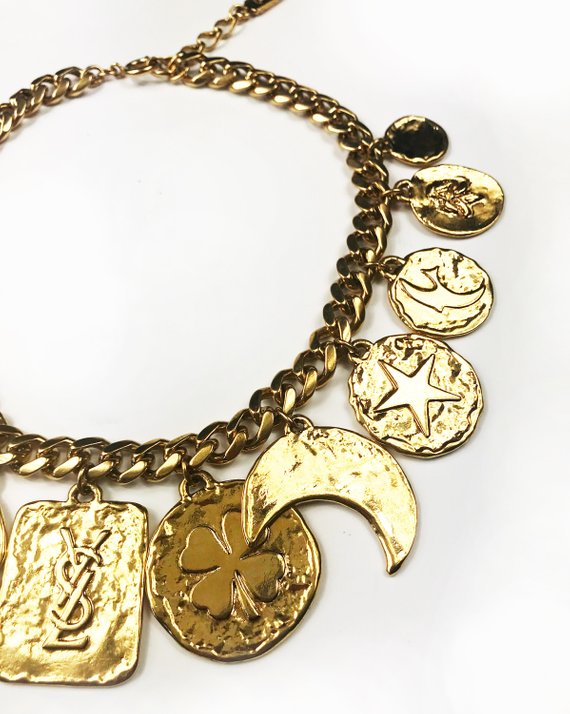 Fruit Vintage rare 1980s Yves Saint Laurent 'lucky charm' medallion necklace with textured logo. It features heavy gold plating in a deep yellow tone and various iconic YSL symbols such as the moon, clover, heart and bird.