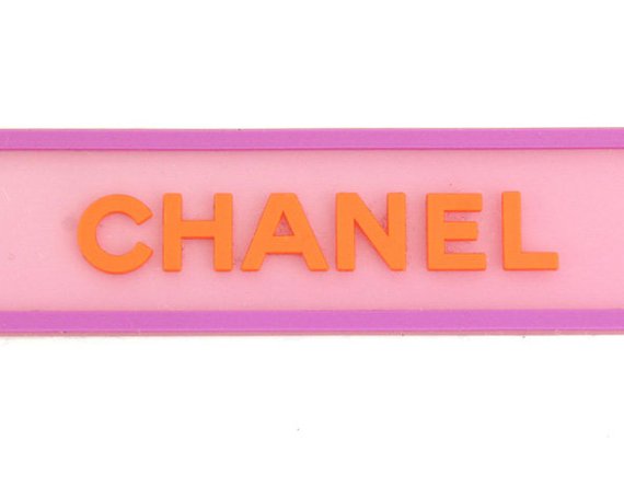 Fruit Vintage Chanel pink and orange rubber logo cuff bracelet with large CHANEL text logo to the centre and two clover symbols either side.