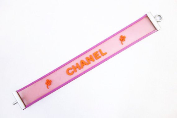 Fruit Vintage Chanel pink and orange rubber logo cuff bracelet with large CHANEL text logo to the centre and two clover symbols either side.