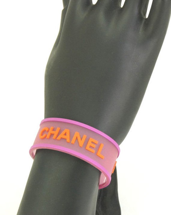 Fruit Vintage Chanel pink and orange rubber logo cuff bracelet with large CHANEL text logo to the centre and two clover symbols either side.