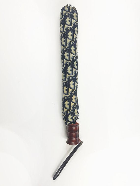 FRUIT vintage Christian Dior navy oblique logo umbrella dating to the late 1970s-early 1980s. This compact umbrella is in working condition with a matching cover, features the classic Christian Dior trotter/oblique print all over, Christian Dior logo text, telescoping stick and faux wood handle.