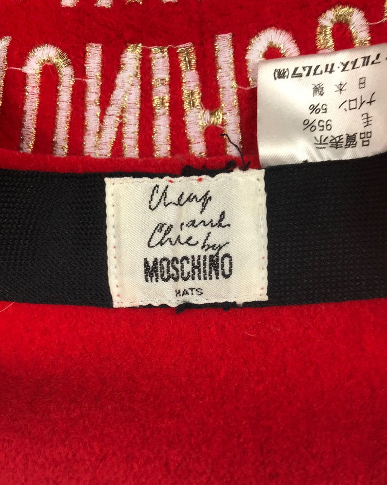 FRUIT Vintage Moschino logo beret hat. It features large embroidered gold text with the slogal "Moschinon Moschinoff" and a classic beret hat shape.