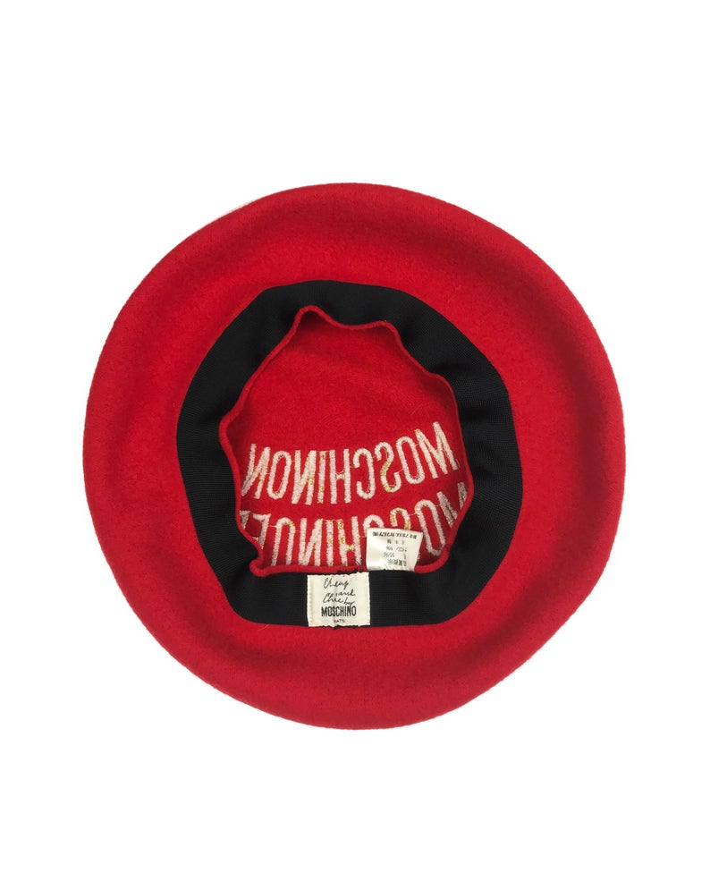 FRUIT Vintage Moschino logo beret hat. It features large embroidered gold text with the slogal "Moschinon Moschinoff" and a classic beret hat shape.