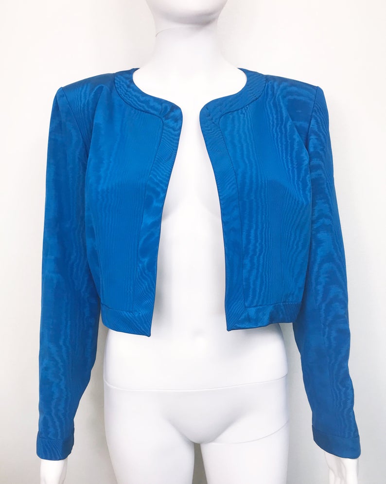 FRUIT Vintage Yves Saint Laurent Rive Gauche turquoise blue crop jacket dating to the 1980s. In near mint condition, this amazing piece features bright green lining and very large blue glass features buttons to each cuff.