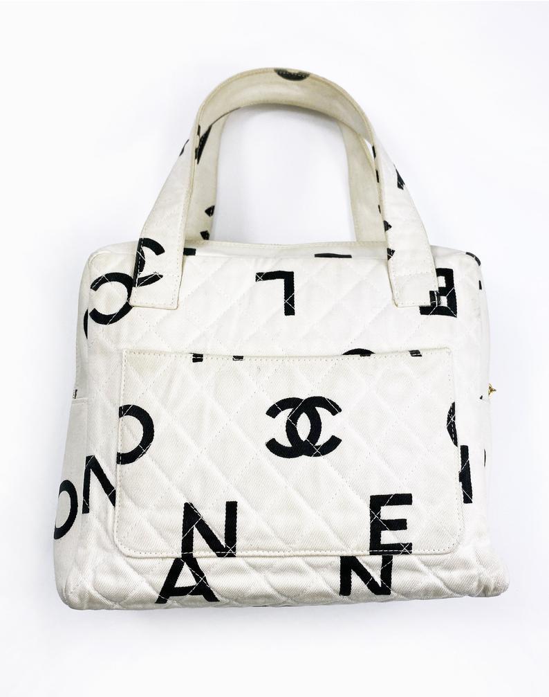 Fruit Vintage Chanel 1997 white/ black quilted logo canvas mini zipper tote makeup vanity bag. It includes 2 external pouch pockets, a logo ball zipper pull, full leather lining, and internal zipper pocket with Chanel logo pull. As seen on Ariana Grande.