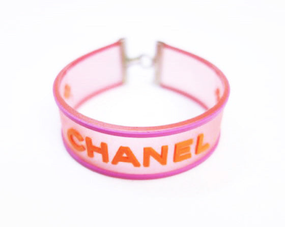 Fruit Vintage Chanel pink and orange rubber logo cuff bracelet with large CHANEL text logo to the centre and two clover symbols either side.