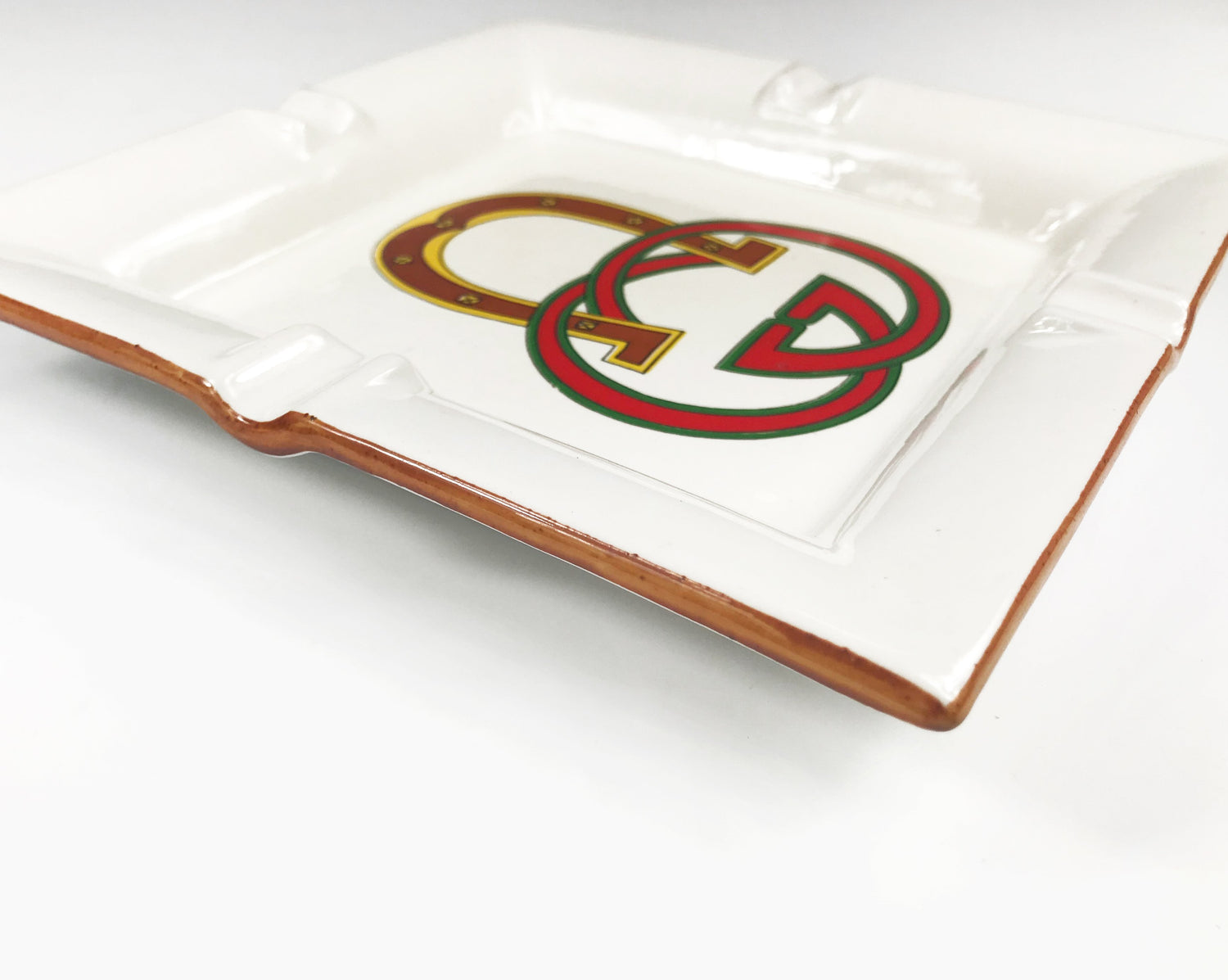 FRUIT Vintage Gucci hand painted 1980's porcelain logo ashtray or change tray. Features a classic ashtray shape, brown trim and Gucci suede logo fabric and mark at base. This is a very special piece!