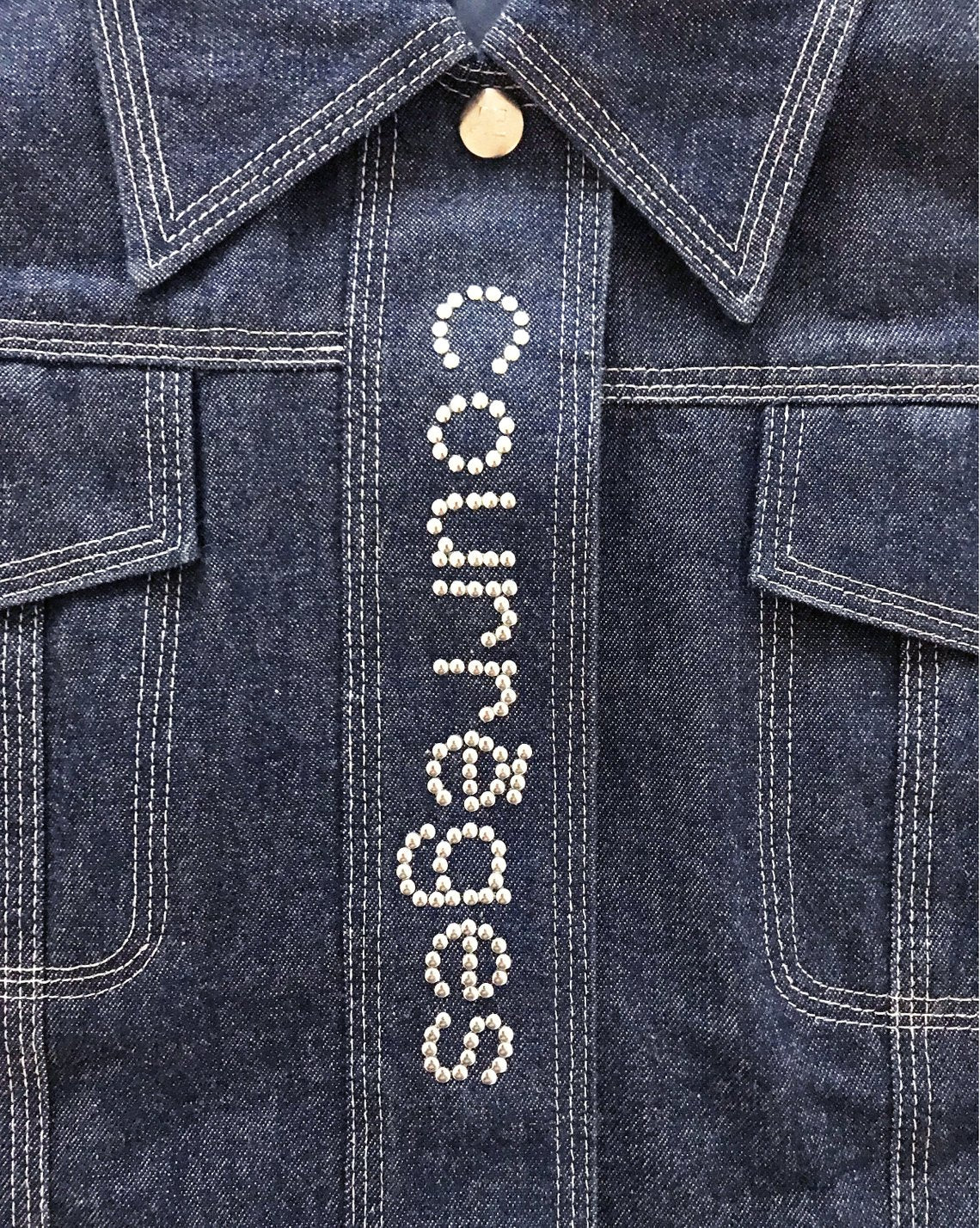 Fruit Vintage Courreges denim logo dress. Features a large silver logo at front, top stitching and logo buttons. Can also be fully unbuttoned and worn as coat/duster jacket.