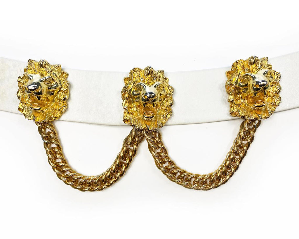 Fruit Vintage iconic Judith Leiber lion head belt with drop chains. This piece is amazing! It features 3 very large gold tone metal lions heads with drop chains on a white leather belt.