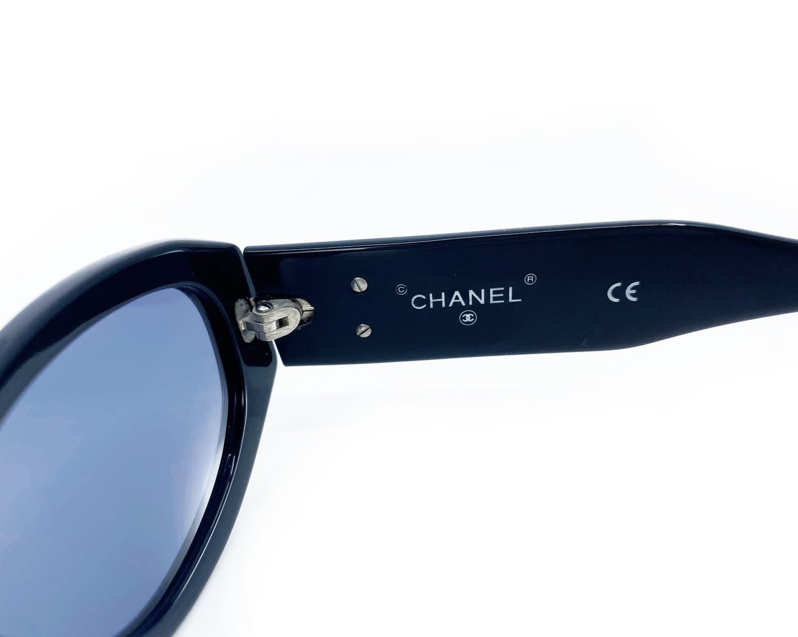 Fruit Vintage Chanel 1990s studded logo sunglasses. They feature silver screw shaped studs to the front of the frame and Chanel CC logo monograms to each side.