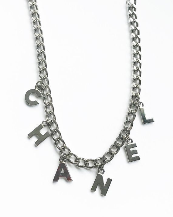 Fruit Vintage Chanel logo monogram letter chain belt in classic silver. Features a hook closure and logo drop Chanel CC charm.