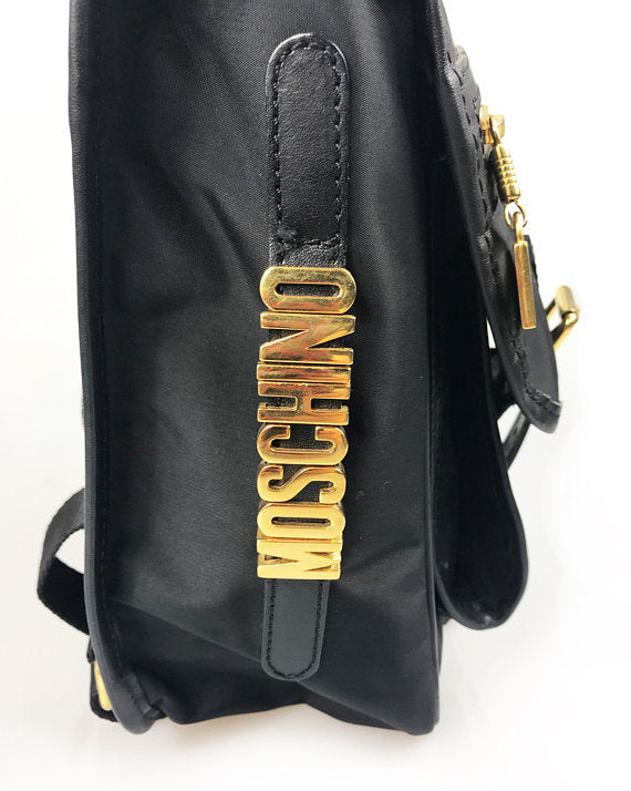 FRUIT Vintage Moschino mini backpack bag with the iconic Moschino gold lettering logo to one side, classic Moschino M logo zipper pull, and Redwall logo lining.