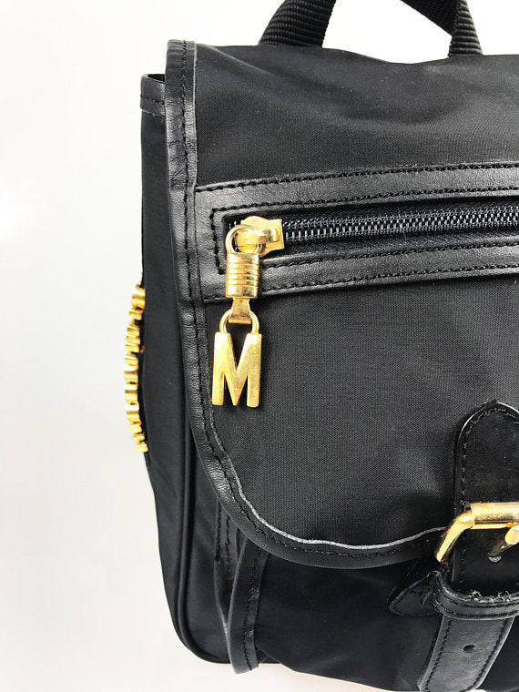 FRUIT Vintage Moschino mini backpack bag with the iconic Moschino gold lettering logo to one side, classic Moschino M logo zipper pull, and Redwall logo lining.