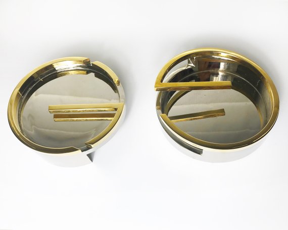 Fruit Vintage rare 1980's Gucci Logo double G ashtray set comprised of two interlocking gold and silver metal G-Shaped trays. This is the most amazing vintage designer home piece!