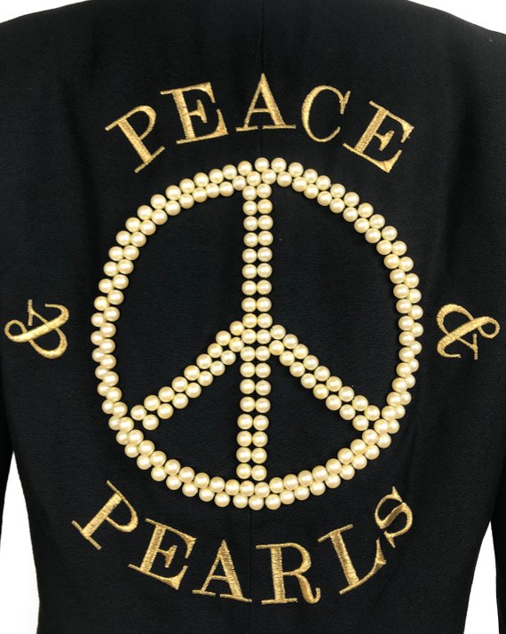FRUIT Vintage rare Moschino Black Peace and Pearls jacket dating to 1989 in Mint condition. Hand sewn with a large pearl peace sign and the iconic Moschino monogram slogan text embroidered in gold.