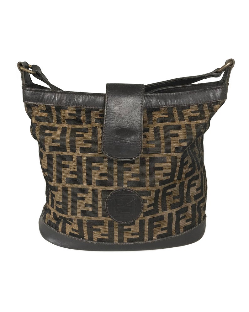 FRUIT Vintage Fendi Zucca cross body bucket bag dating to the 1980s. It features the classic Fendi Zucca monogram canvas, front embossed logo, top push button closure and long adjustable cross body strap..