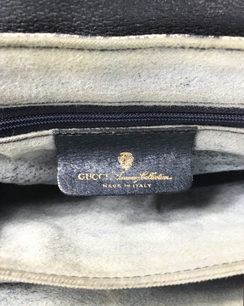 FRUIT Vintage Gucci 1980s logo clutch bag in a navy coated Gucci monogram canvas. It features a classic gucci navy and red racing stripe front detail, internal zipper pocket and separated pockets.