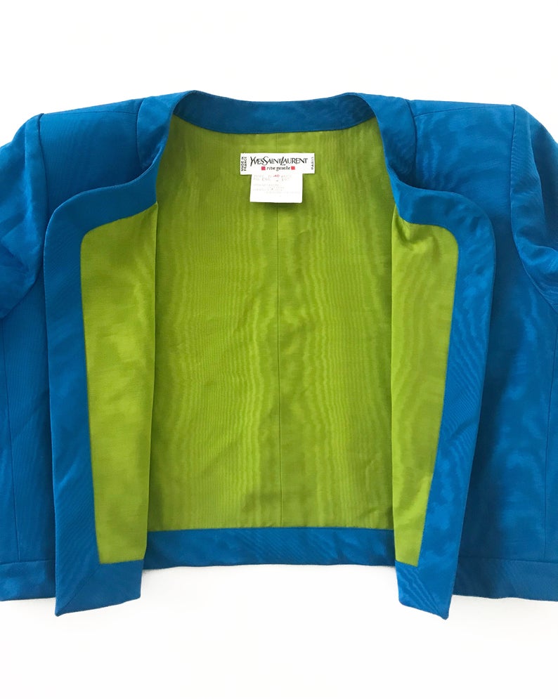 FRUIT Vintage Yves Saint Laurent Rive Gauche turquoise blue crop jacket dating to the 1980s. In near mint condition, this amazing piece features bright green lining and very large blue glass features buttons to each cuff.