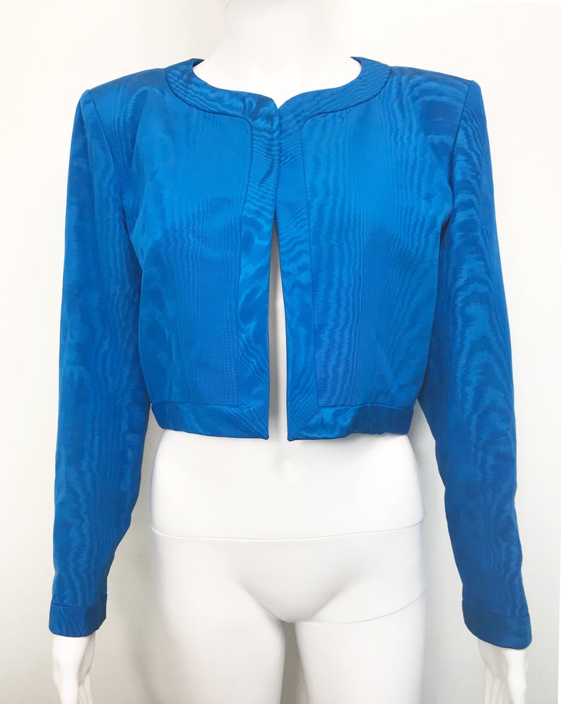 FRUIT Vintage Yves Saint Laurent Rive Gauche turquoise blue crop jacket dating to the 1980s. In near mint condition, this amazing piece features bright green lining and very large blue glass features buttons to each cuff.