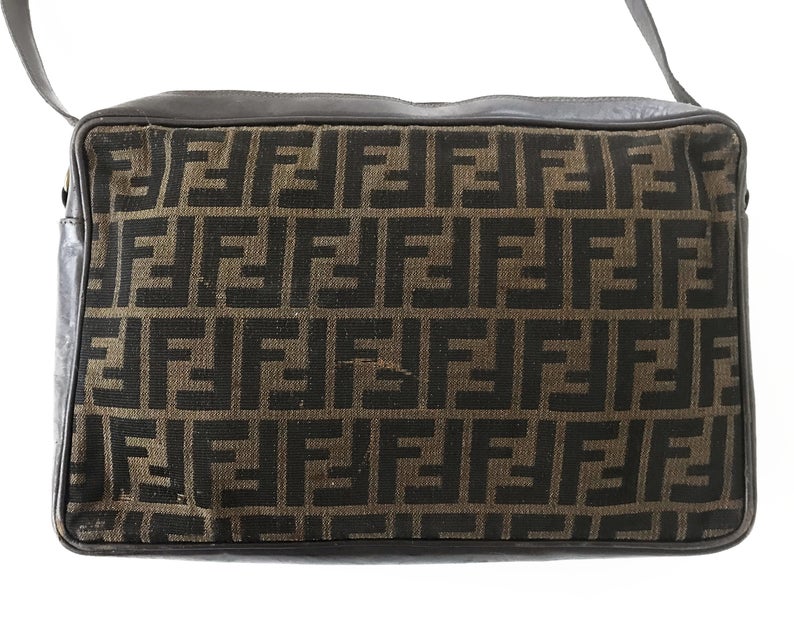 FRUIT Vintage Fendi Zucca cross body satchel handbag dating to the 1980s. It features the classic Fendi Zucca monogram canvas, front embossed logo, top zipper closure and long adjustable cross body strap bag.