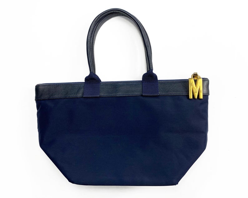 FRUIT Vintage Moschino mini tote bag with the iconic Moschino gold lettering at front. Features a top zipper closure with M logo zipper pull, Moschino logo lining, Moschino Redwall authenticity stamp and logo plaque at side.