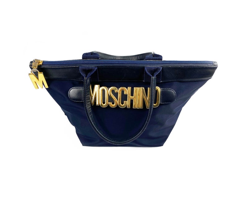 FRUIT Vintage Moschino mini tote bag with the iconic Moschino gold lettering at front. Features a top zipper closure with M logo zipper pull, Moschino logo lining, Moschino Redwall authenticity stamp and logo plaque at side.
