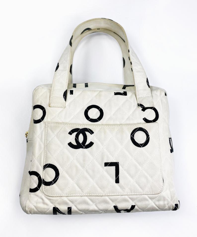 Fruit Vintage Chanel 1997 white/ black quilted logo canvas mini zipper tote makeup vanity bag. It includes 2 external pouch pockets, a logo ball zipper pull, full leather lining, and internal zipper pocket with Chanel logo pull. As seen on Ariana Grande.