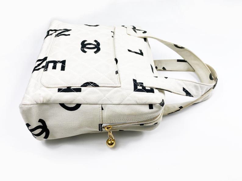 Fruit Vintage Chanel 1997 white/ black quilted logo canvas mini zipper tote makeup vanity bag. It includes 2 external pouch pockets, a logo ball zipper pull, full leather lining, and internal zipper pocket with Chanel logo pull. As seen on Ariana Grande.