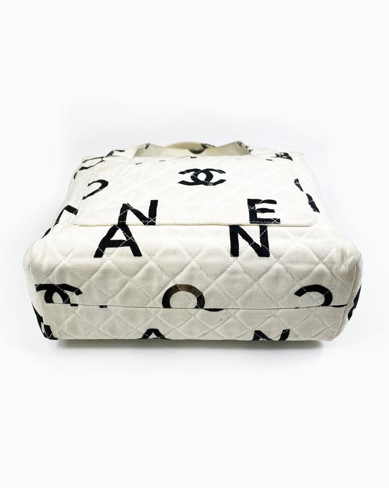 Fruit Vintage Chanel 1997 white/ black quilted logo canvas mini zipper tote makeup vanity bag. It includes 2 external pouch pockets, a logo ball zipper pull, full leather lining, and internal zipper pocket with Chanel logo pull. As seen on Ariana Grande.