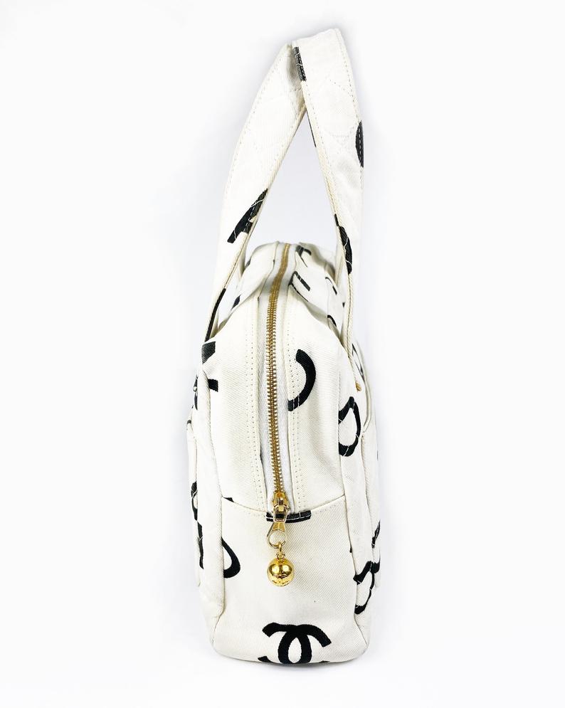 Fruit Vintage Chanel 1997 white/ black quilted logo canvas mini zipper tote makeup vanity bag. It includes 2 external pouch pockets, a logo ball zipper pull, full leather lining, and internal zipper pocket with Chanel logo pull. As seen on Ariana Grande.